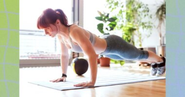 fit woman performing pushups in a bright living space next to floor to ceiling windows on bright sunny day