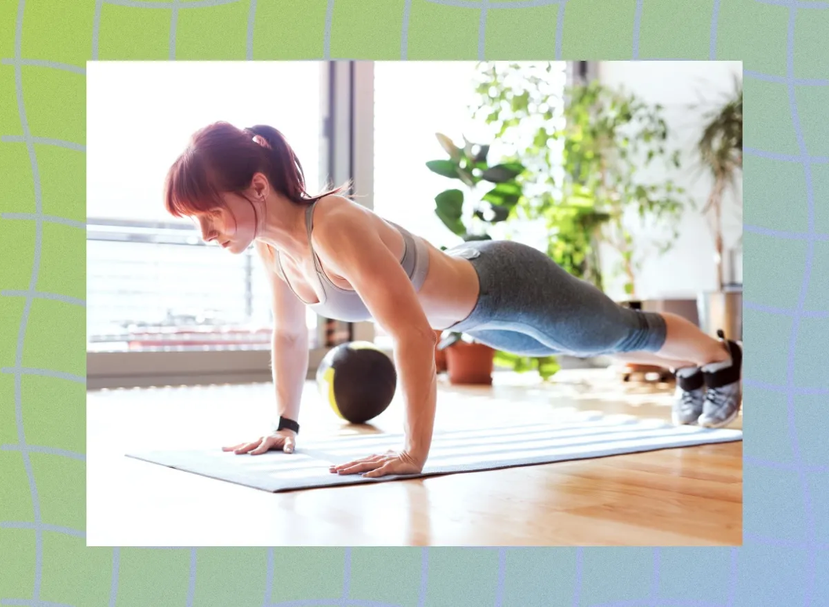 fit woman performing pushups in a bright living space next to floor to ceiling windows on bright sunny day