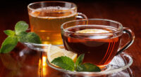 Hot green tea with mint and black tea with lemon and mint in glass cups. Side view. Selective focus.