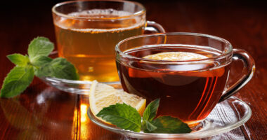 Hot green tea with mint and black tea with lemon and mint in glass cups. Side view. Selective focus.