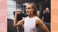 fit, mature brunette woman lifting a kettlebell in the gym during a workout class