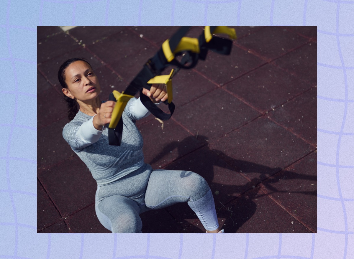 focused middle-aged woman training with suspension straps