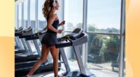 fit woman running on treadmill at the gym in front of floor to ceiling windows