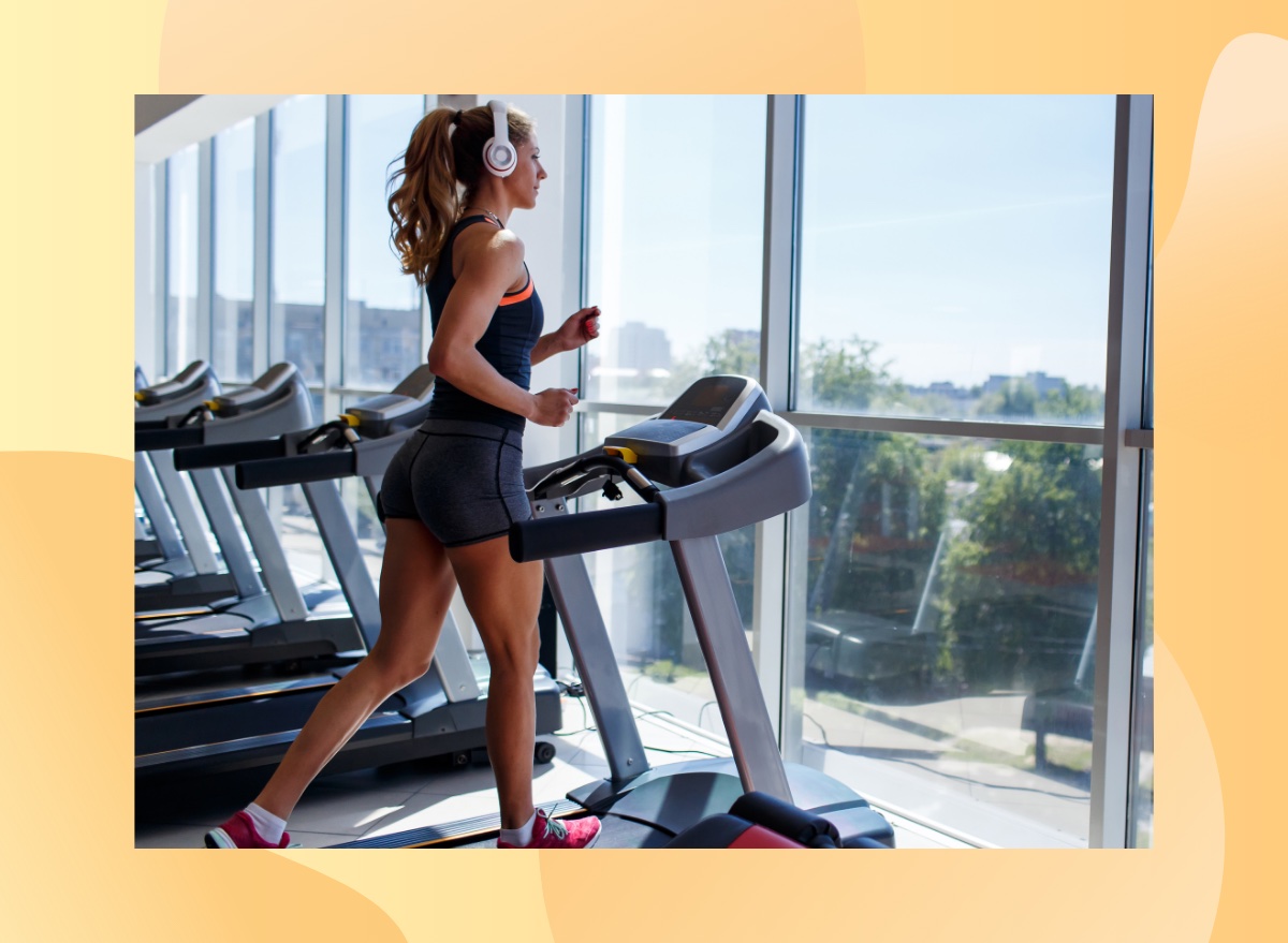 fit woman running on treadmill at the gym in front of floor to ceiling windows