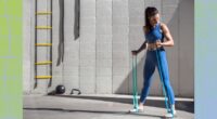 fit woman training with resistance bands, doing arm exercises outdoors