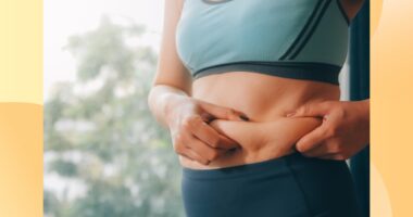 close-up of woman in athletic outfit holding excess belly fat