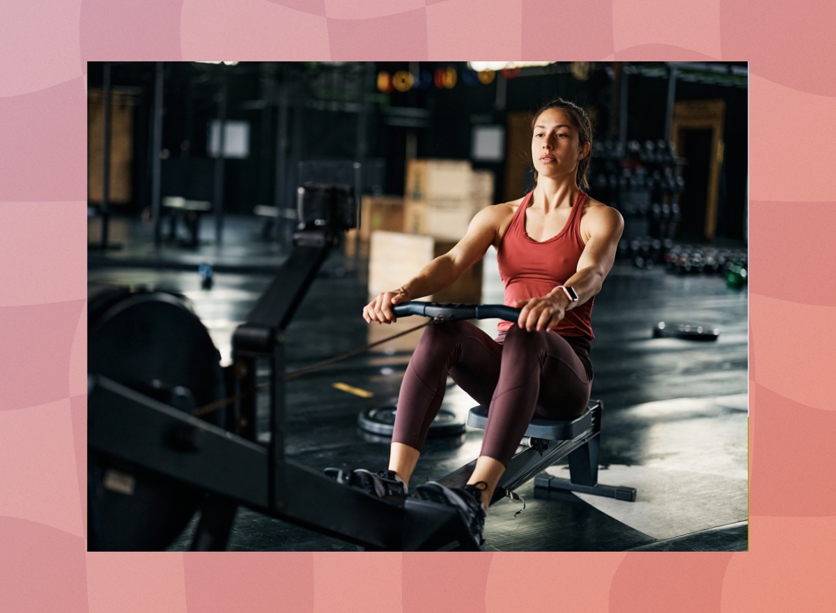 fit, focused brunette woman using a rowing machine at the gym