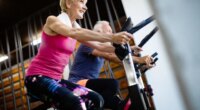 two older adults doing indoor cycling at the gym