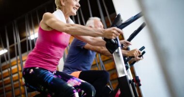 two older adults doing indoor cycling at the gym