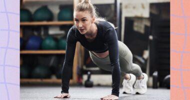 focused blonde woman doing high plank or pushup at the gym