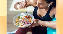 close-up of fitness woman eating healthy lunch while sitting next to exercise ball in bright living space