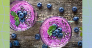 blueberry chia smoothie in two cups on wooden table, surrounded by fresh blueberries