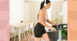 focused brunette woman walking on treadmill in bright apartment