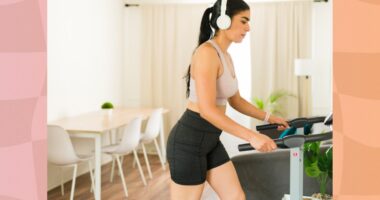 focused brunette woman walking on treadmill in bright apartment