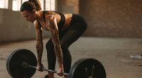 fit, muscular woman doing barbell deadlift exercise