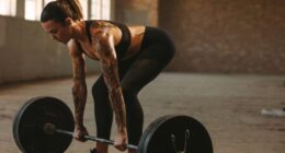 fit, muscular woman doing barbell deadlift exercise