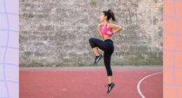 woman doing high knees exercise outdoors on track