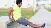 man performing bodyweight dip outside along walking route