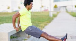 man performing bodyweight dip outside along walking route