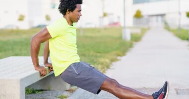 man performing bodyweight dip outside along walking route