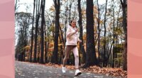 brunette woman running outdoors on trail in the fall with leaves on the ground