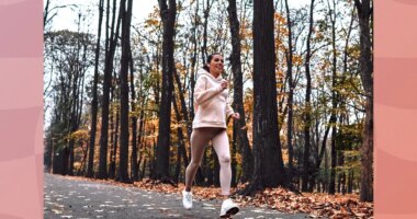 brunette woman running outdoors on trail in the fall with leaves on the ground