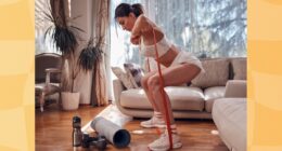 fit, determined brunette woman doing resistance band squats in bright living room