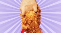 A chicken tender from KFC, dripping with sauce and held in a woman