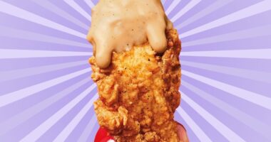 A chicken tender from KFC, dripping with sauce and held in a woman