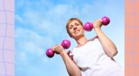 mature woman lifting weights outdoors with blue sky behind her