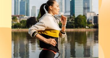 fit brunette woman jogging along river in the city