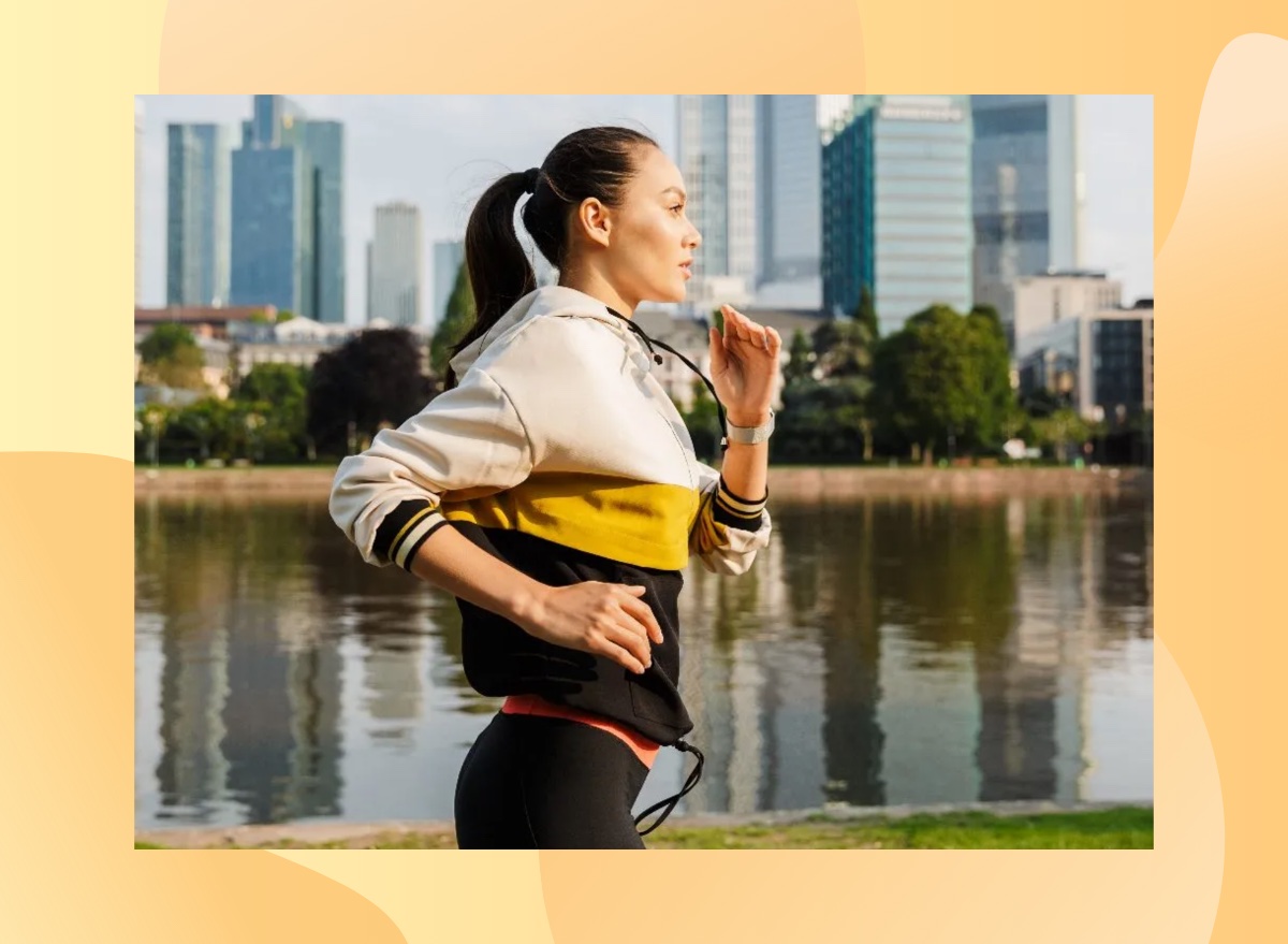 fit brunette woman jogging along river in the city