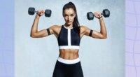 focused brunette woman doing dumbbell overhead press in front of gray backdrop