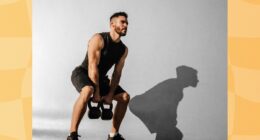 focused, muscular man doing kettlebell squat