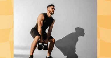 focused, muscular man doing kettlebell squat