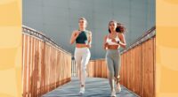 two fit women running outdoors on small bridge