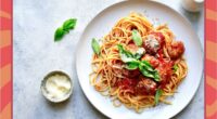 a plate of spaghetti and meatballs on a designed background