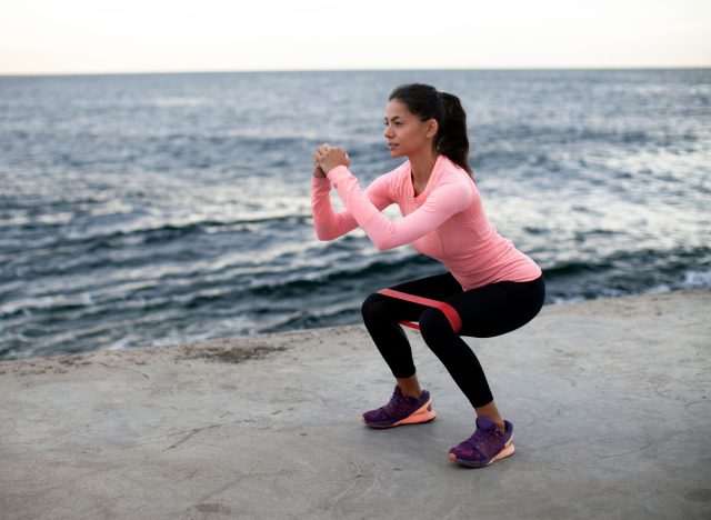 fitness woman doing banded squats, concept of resistance band exercises to burn body fat