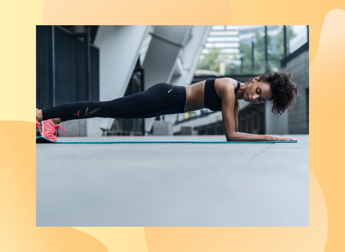 fit woman doing forearm plank on exercise mat outdoors