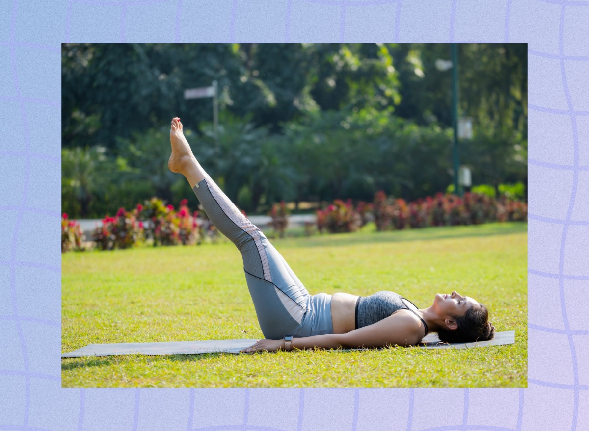 fit, mature woman doing leg raises exercise on yoga mat in grassy field