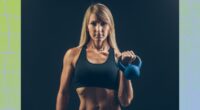 fit blonde woman holding kettlebell in front of black backdrop