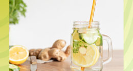 cucumber lemon ginger infused water in a glass next to a cutting board with a green border