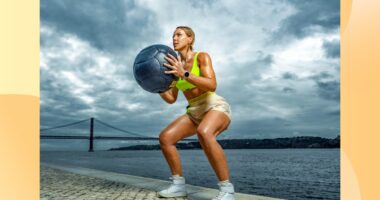 fit woman holding medicine ball while squatting