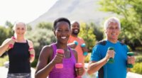 group of active people using dumbbells during walking workout outside