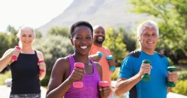 group of active people using dumbbells during walking workout outside