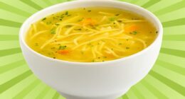 A bowl of chicken noodle soup set against a vibrant background.