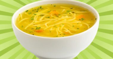 A bowl of chicken noodle soup set against a vibrant background.