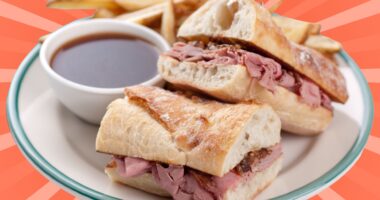 A classic French dip sandwich with fries and au jus set against a vibrant background