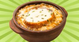 A crock of cheesy French onion soup set against a vibrant background