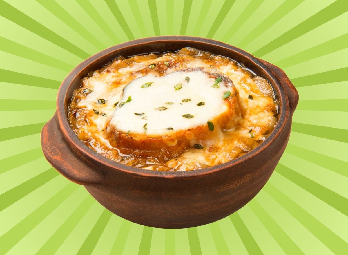 A crock of cheesy French onion soup set against a vibrant background